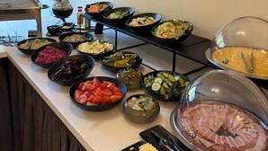 Ein Buffet mit verschiedenen Speisen, eine Vase mit Trockenpflanzen und ein Gemälde an der Wand.