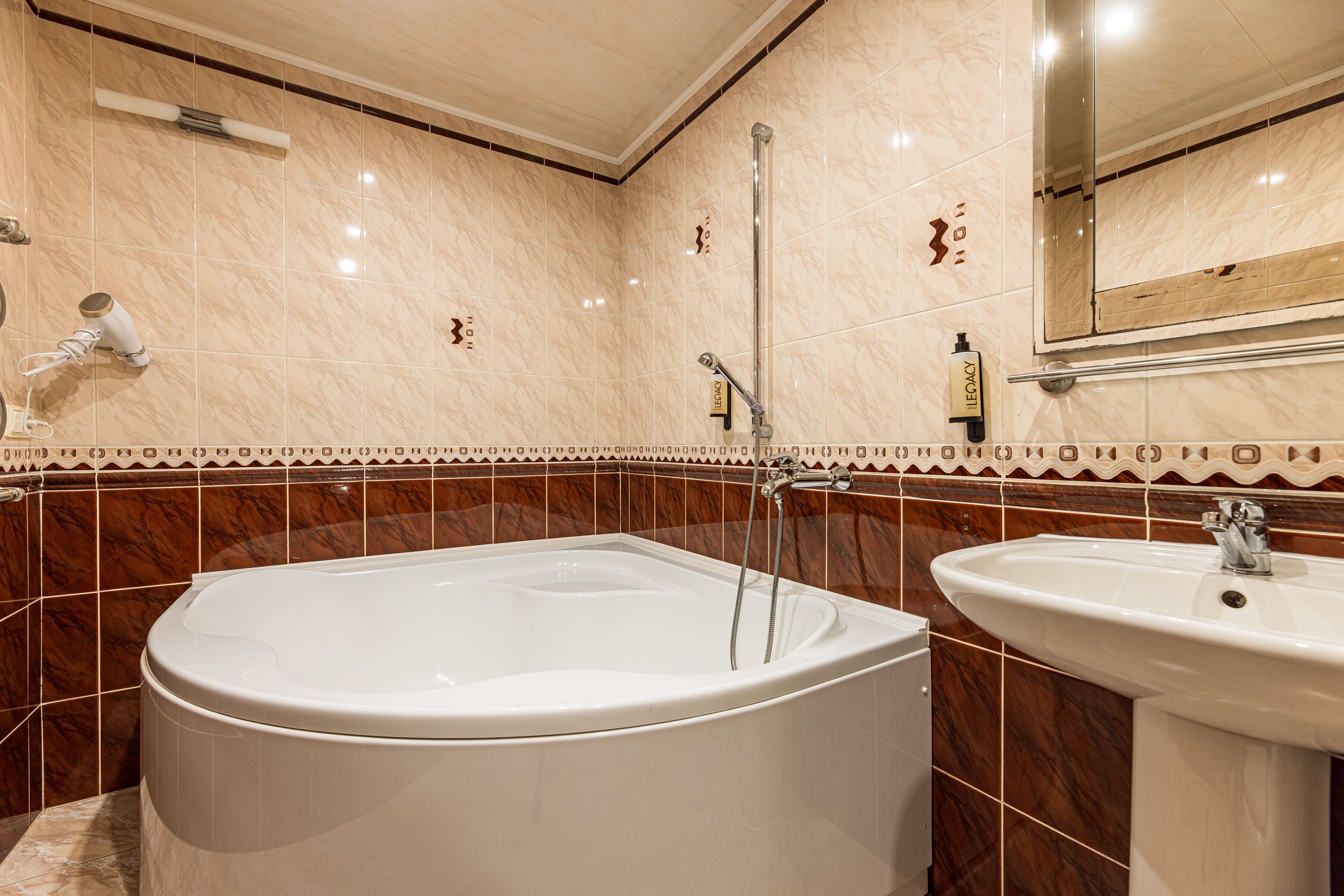 A bathroom with a large bathtub, a sink, and a mirror.
