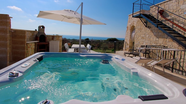 A hot tub with a view of the sea, outdoor seating, and a stone wall. - The Dream Residence 241 (Salve)