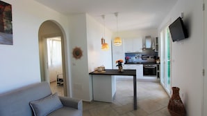 A modern kitchen with white cabinets, a dining table, and pendant lights. - The Dream Residence 241 (Salve)