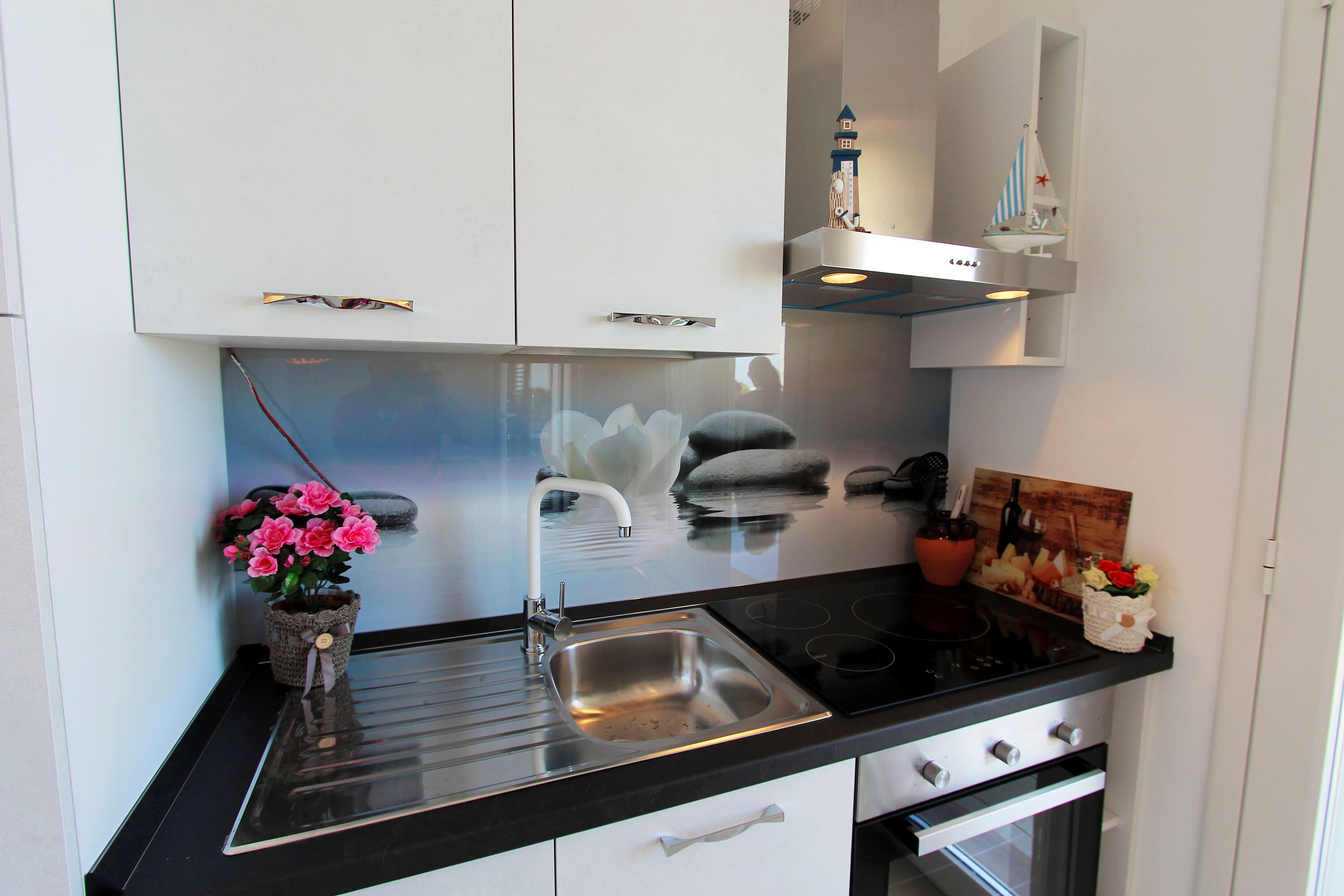 A modern kitchen with a black countertop, stainless steel sink, and white cabinets.