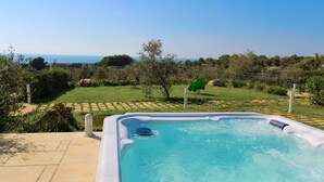 Un bain à remous avec une vue dégagée sur la mer et un jardin clos.