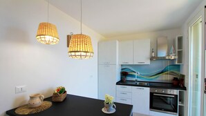 Une cuisine moderne avec des meubles blancs, un plan de travail noir et deux suspensions en osier.