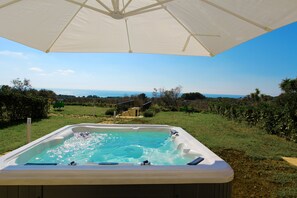 A hot tub with a clear view of the ocean and a grassy area in the background. - The Dream Residence 244 (Salve)