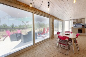 Enjoy a spacious room with a sliding glass door leading to an outdoor patio area, a dining table for four, and a kitchen area.