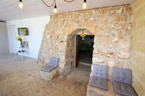 Relax in a warm, inviting space with cushioned seating areas against a rustic stone wall.