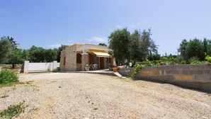 A stone building with a yellow awning, a gravel driveway, and a stone wall. - Villetta 54 (Salve)