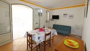 A dining area with a table, chairs, a sofa, and a TV mounted on the wall. - Villetta 54 (Salve)