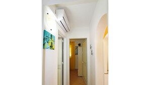 A narrow hallway with an air conditioning unit mounted on the wall, a door leading to another room, and a painting on the wall. - Villetta 54 (Salve)