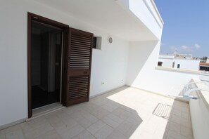 A balcony with a sliding door, a small window, and a tiled floor. - Villetta Duca (Castrignano del Capo)