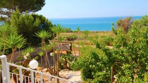 A coastal garden with a view of the sea, featuring various plants and a white railing. - Villetta Mare 464 (Patu)