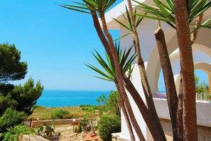 A coastal view with palm trees and a white building.