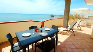 A balcony with a table set for two, overlooking the sea. - Beach Apartment in Puglia (Salve)