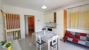 Un espace de vie compact comprenant un coin repas, une kitchenette et un canapé.