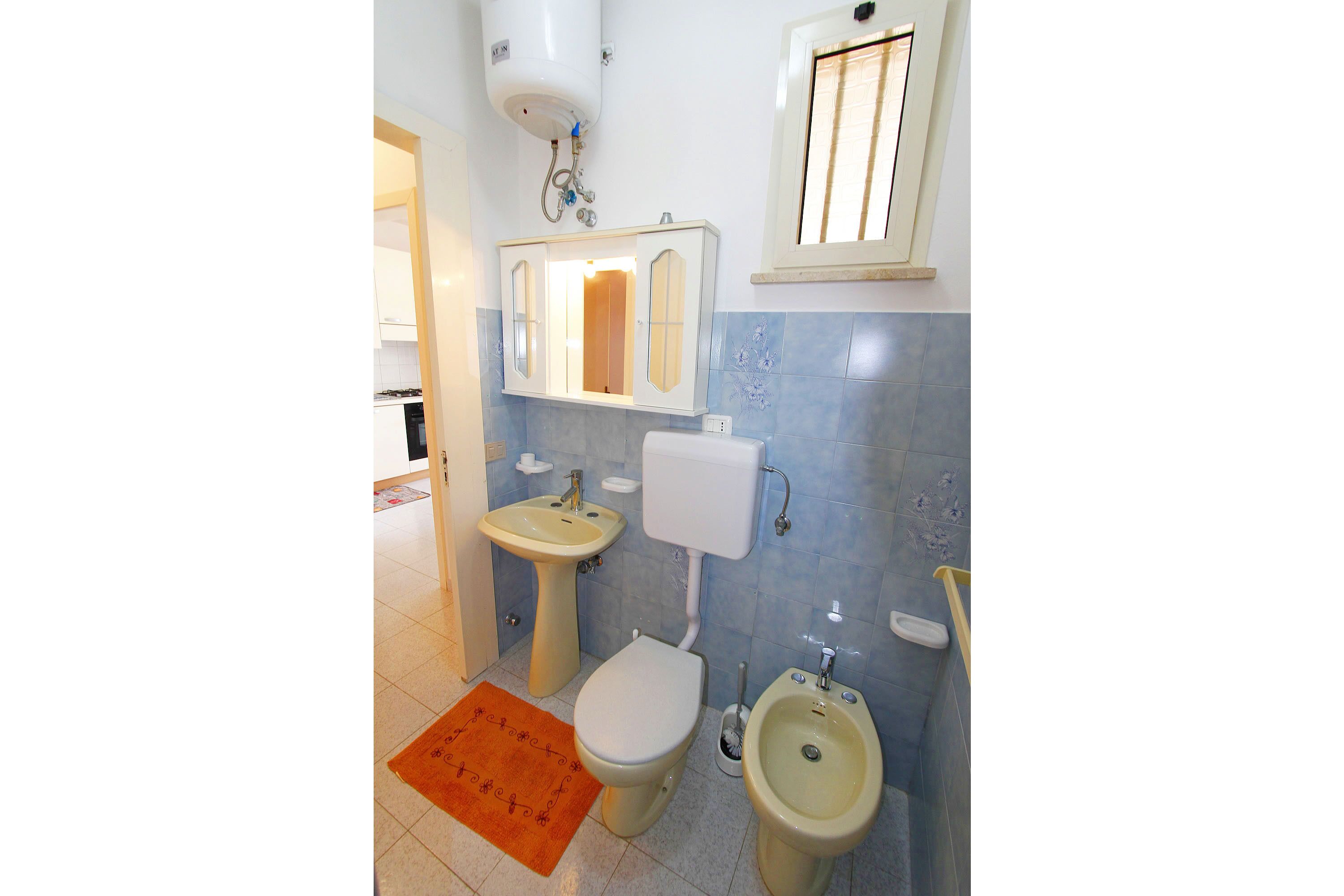 A bathroom with a toilet, bidet, sink, and mirror.