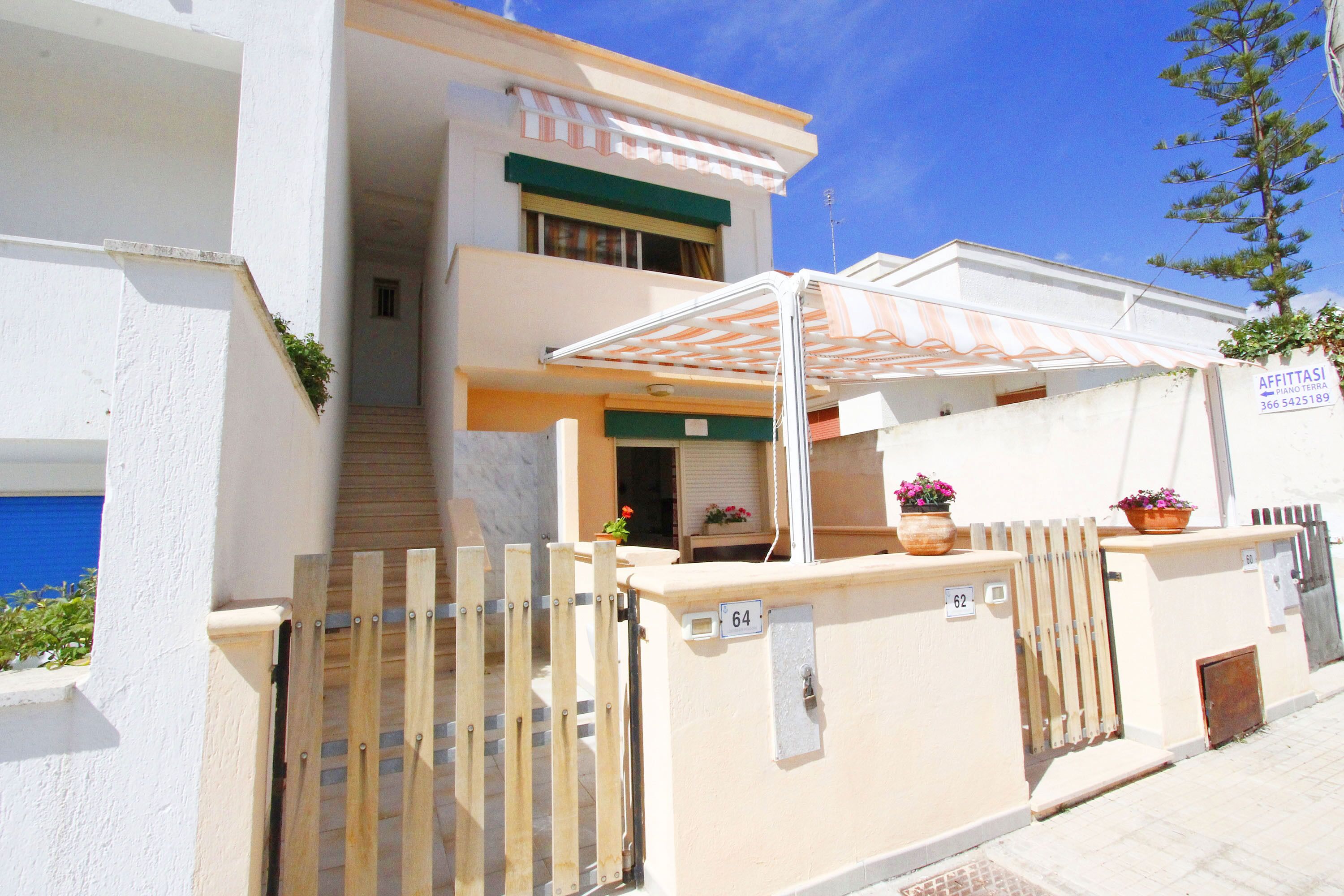 A two-story building with a covered entrance and a gated driveway.