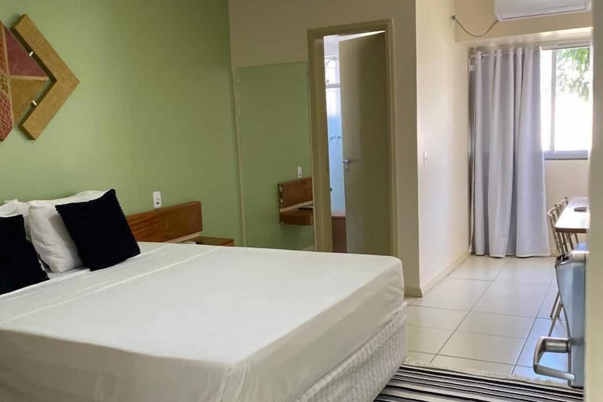 Ein Hotelzimmer mit einem Bett, einem Spiegel, einer Tür zu einem Badezimmer und einem Fenster mit Vorhängen.