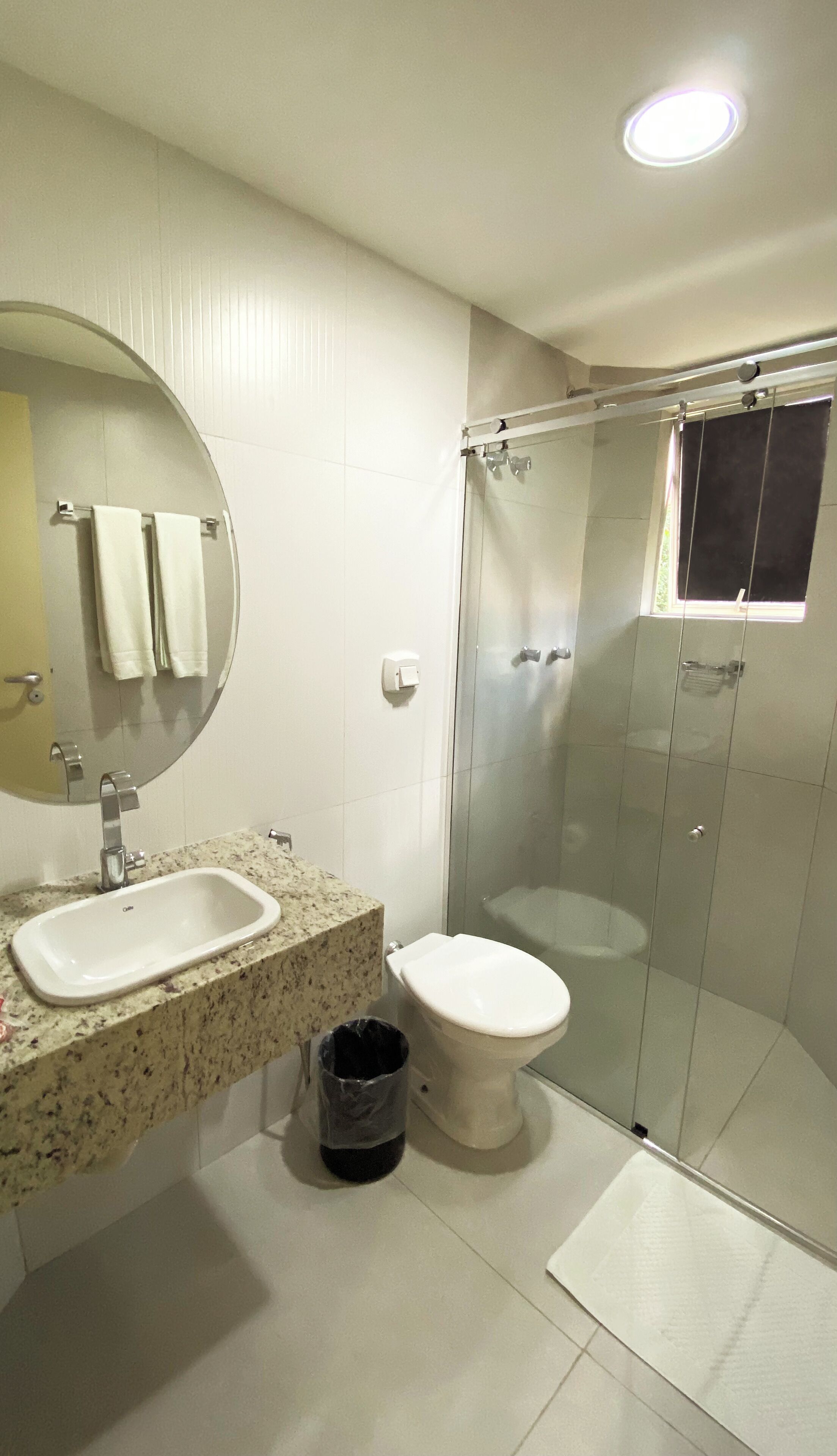 Un baño con lavamanos, inodoro y cabina de ducha de vidrio.