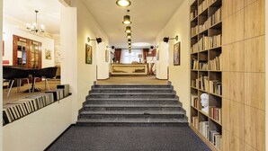 Una biblioteca con una escalera que lleva a una zona de escritorio, estanterías y una araña.
