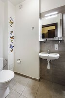 A bathroom with a toilet, sink, mirror, and decorative butterfly wall stickers.