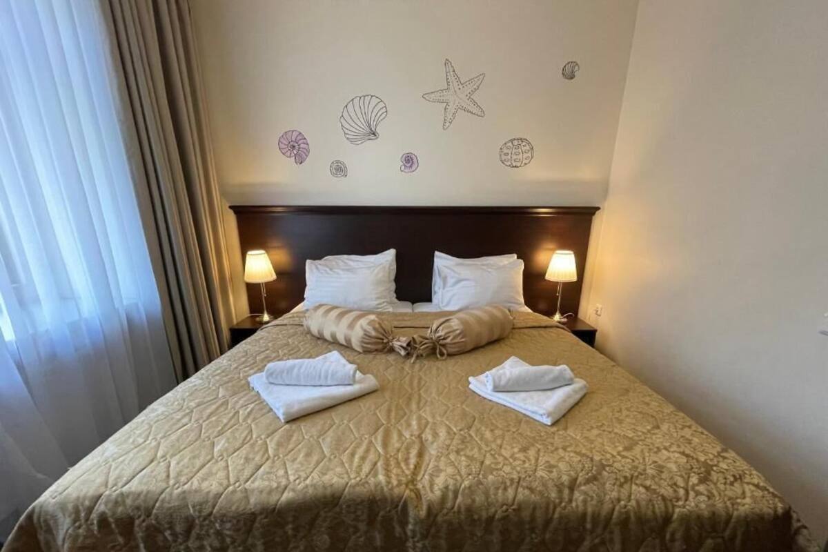 A hotel room with a bed, two bedside lamps, and a wall decorated with sea-themed stickers.