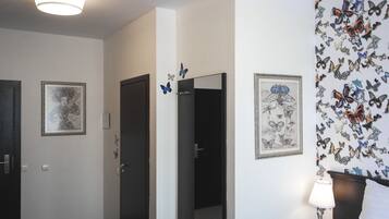 Habitación de hotel con cama, mesita de noche, lámpara y decoración de mariposas en la pared.