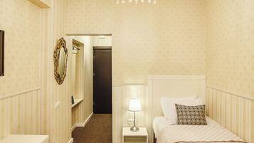 A hotel room with a bed, bedside table, lamp, and a mirror on the wall.