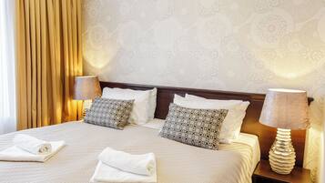 A neatly made bed with two pillows, a bedside lamp, and a folded towel on a hotel room bed.