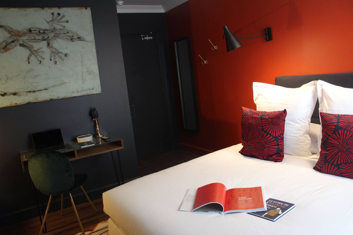 A hotel room with a bed, a desk, and a chair.