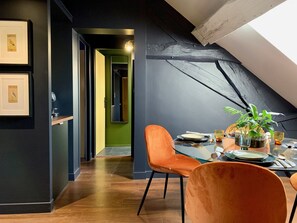 A dining area with a high ceiling, a skylight, and a view of a green room. - Le Globe (Meursault)