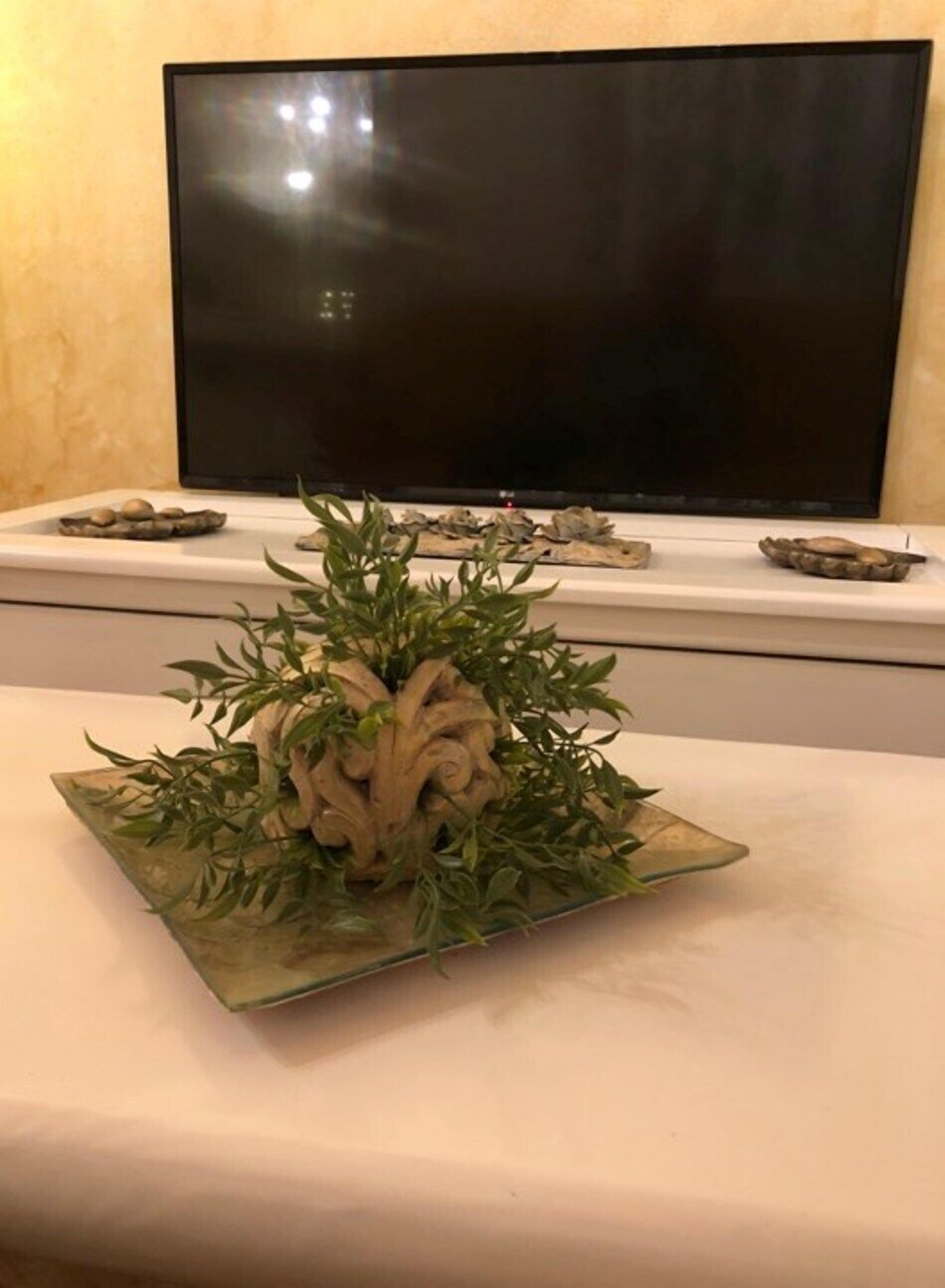A table with a decorative centerpiece featuring green leaves and beige elements.