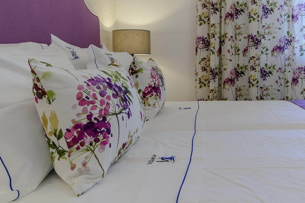 A neatly made bed with floral-patterned pillows and a white bedspread.