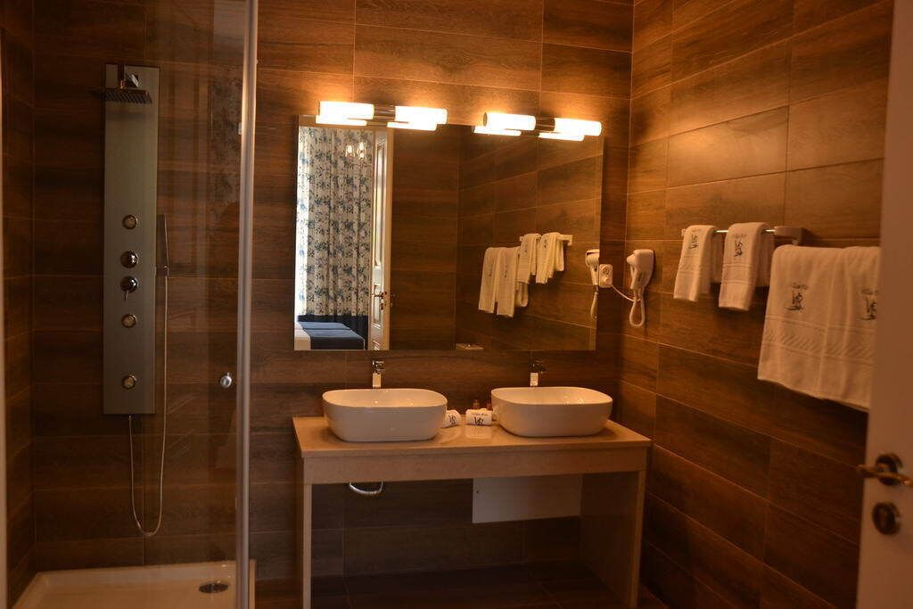 Uma casa de banho moderna com chuveiro em cabine de vidro, duas pias e um espelho grande com iluminação embutida.