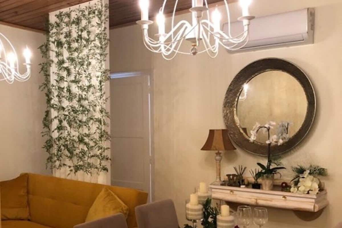 Ein Essbereich mit einem Tisch für vier Personen, einer Chandelüster, einem Spiegel und einem gelben Sofa.