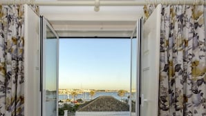 A room with a large window, a ceiling fan, and yellow chairs. - Villa Rio Guest House Suites (Portimão)
