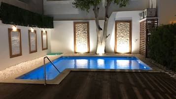 Una piscina al aire libre, sombrillas, sillones reclinables de piscina