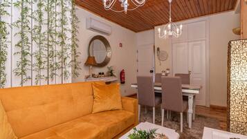 Un salon comprenant un canapé, une table à manger, des chaises et un lustre.