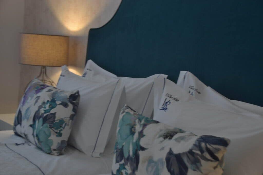 Una cama bien hecha con ropa blanca y almohadas de estampado floral.