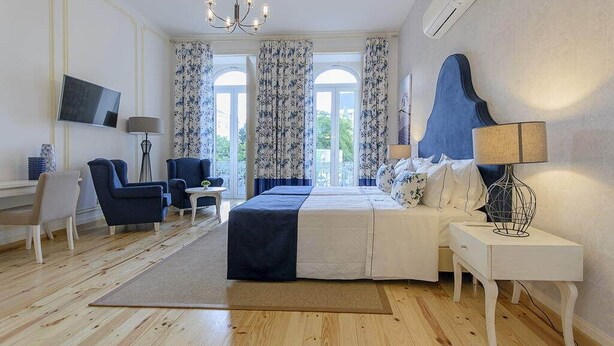 A modern bedroom with a large bed, a desk, a chair, and a TV. - Villa Rio Guest House Suites (Portimão)