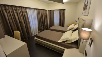 A hotel room with two beds, a desk, a chair, and a lamp.