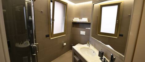 A modern bathroom with a glass-enclosed shower, a sink with a vanity, and two mirrors with framed windows.