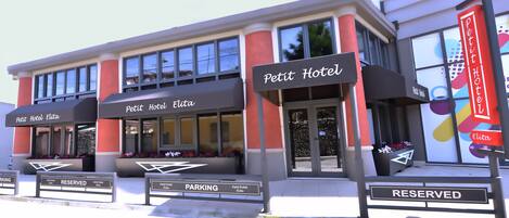 Ein Hotel mit Schildern, auf denen 'Petit Hotel Elita' und 'RESERVIERT' für Parkplätze stehen.