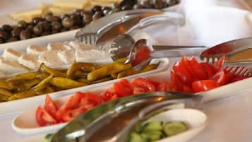 A buffet with various food items including sliced meats, cheeses, olives, and vegetables.