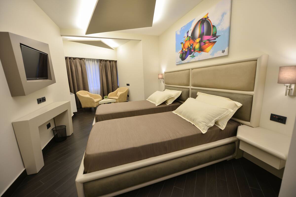 Une chambre d’hôtel avec un grand lit, un téléviseur fixé au mur, un bureau et une chaise.