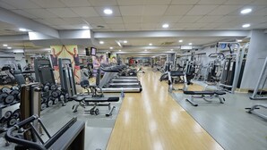 Un gimnasio con cintas de correr, máquinas de pesas y mancuernas.