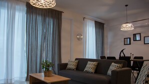 A modern living room with a sofa, a coffee table, and a dining area with chairs and a table. - B&M House (Kissamos)