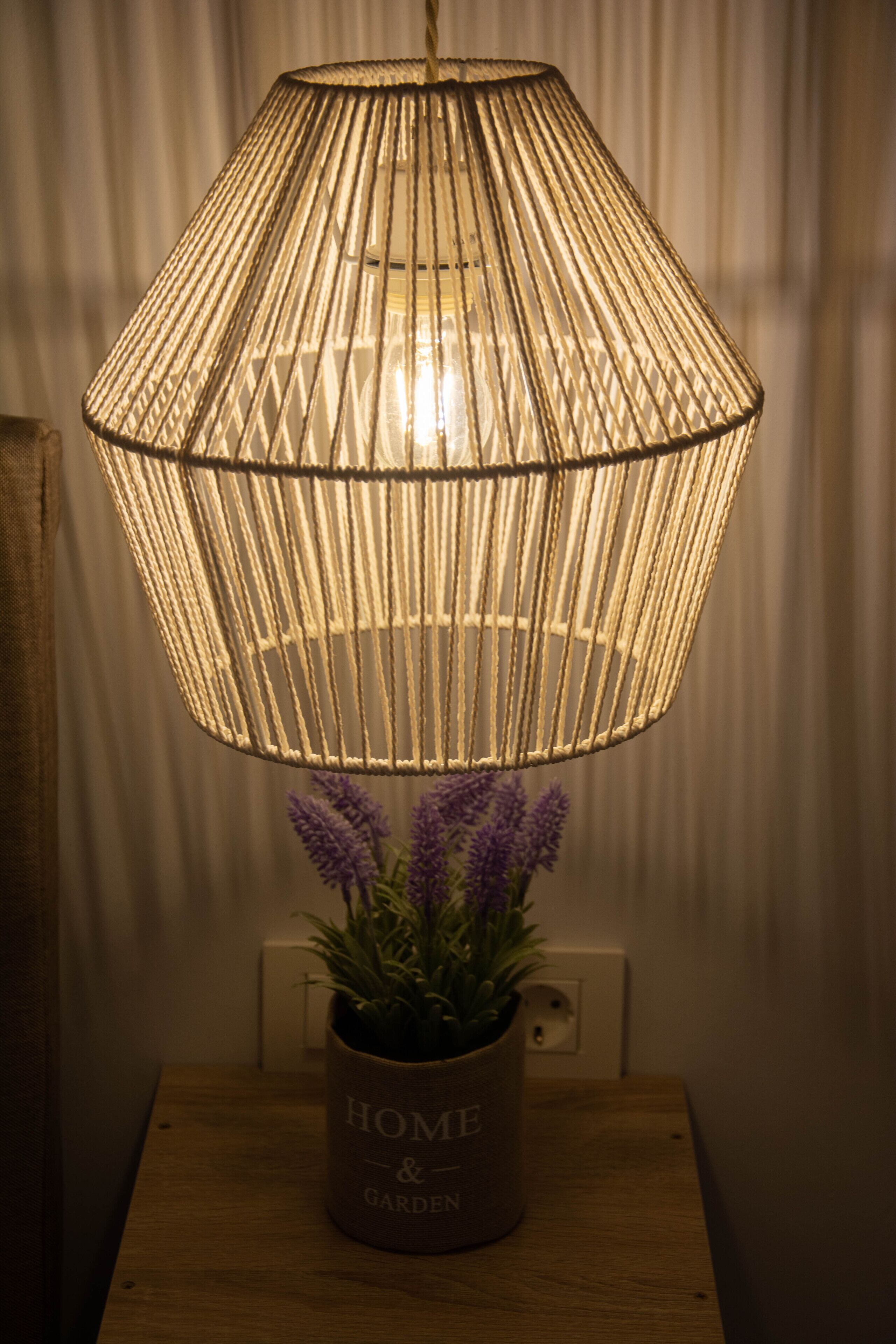 A woven lamp shade over a table with a potted plant labeled "HOME & GARDEN".