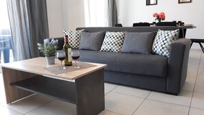 A modern living room with a grey sofa, patterned cushions, a wooden coffee table, and a potted plant. - B&M House (Kissamos)