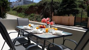 A breakfast table set outdoors with white plates, cups, and a bowl of fruit. - B&M House (Kissamos)