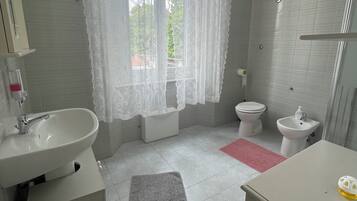 Un baño con un ventanal grande, lavabo, inodoro y bidé.